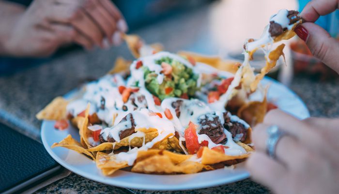 A plate of nachos being shared.