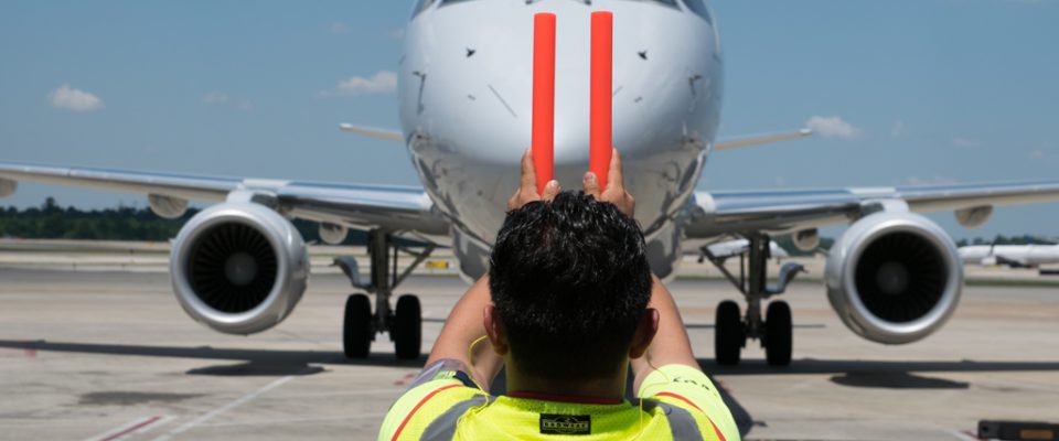 Envoy agent on the ramp guiding aircraft with wands