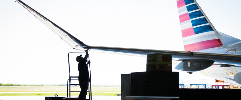 aircraft mechanic standing under plane wing in hangar