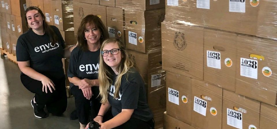 three female envoy employees pose for a photo while volunteering at the north texas food bank