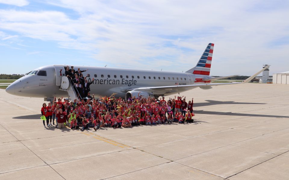 Team Envoy and group of girls pose in front of an Envoy E175 at Purdue University Airport for Girls in Aiviation Day